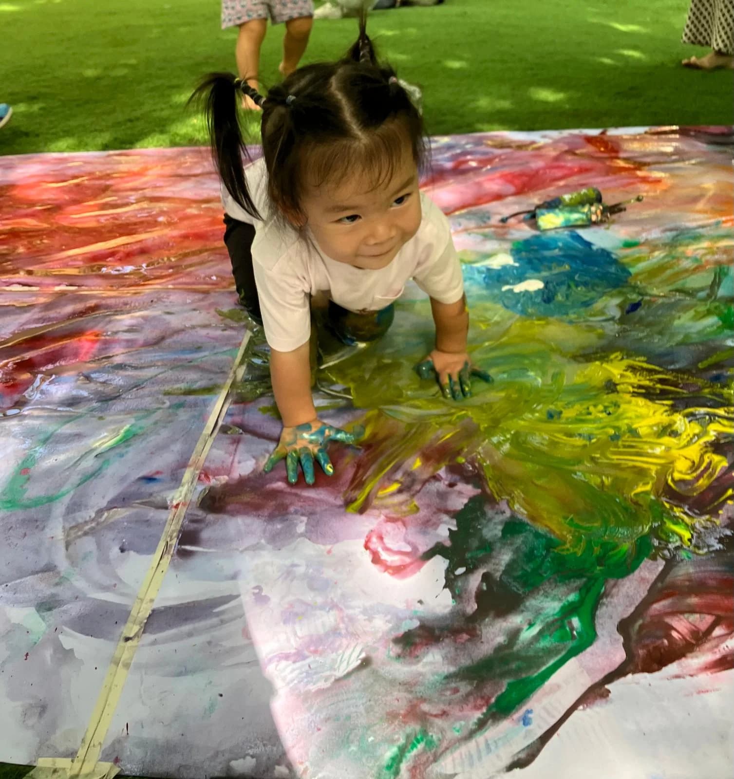 A young child exploring colour through whole-body painting outdoors
