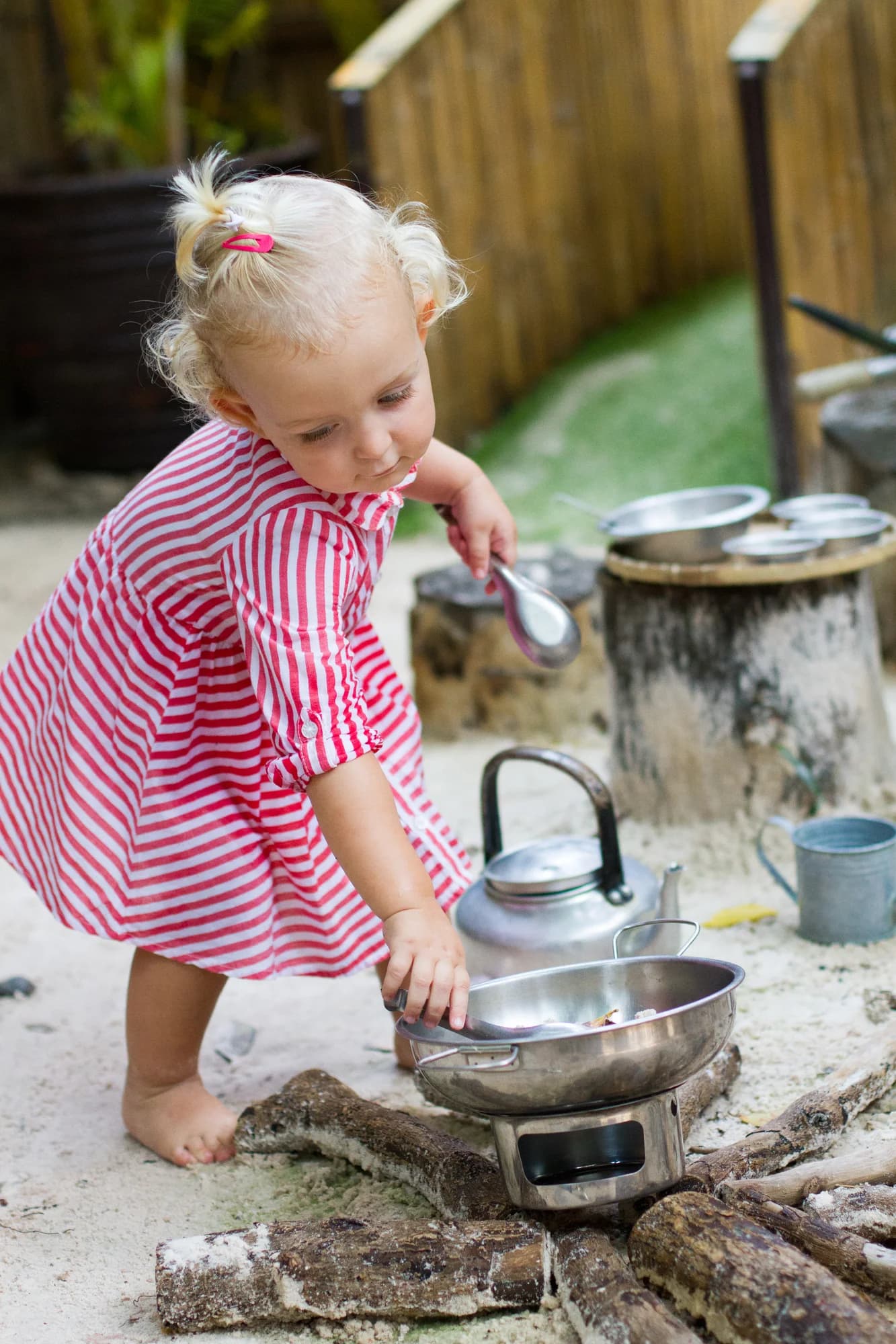 A child exploring pots and pans in the outdoor mud kitchen