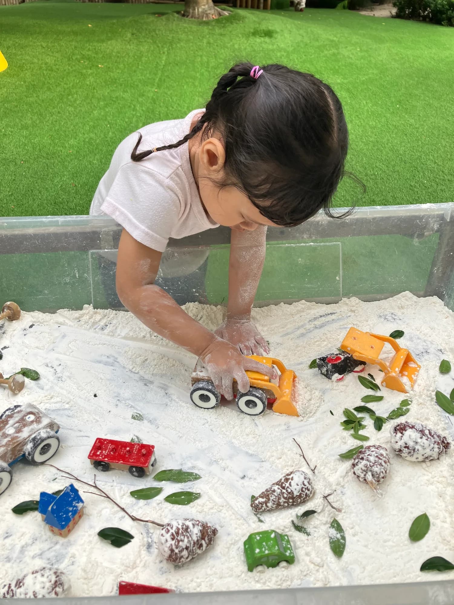 A child moving toy vehicles through a sensory tray