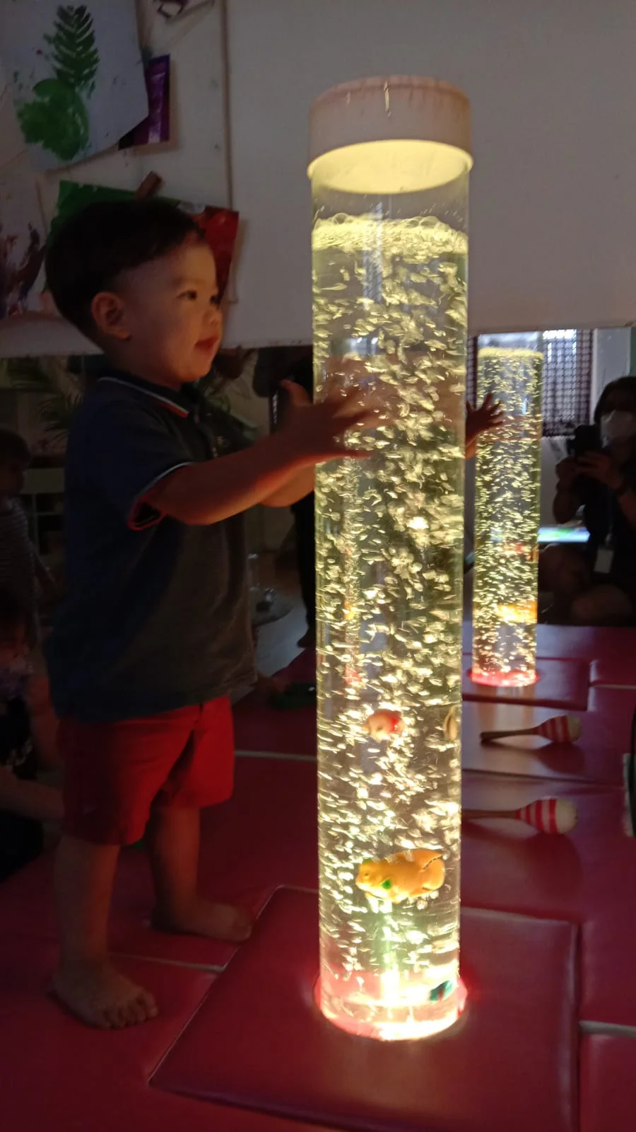 A child exploring a glowing bubble tube in the sensory room